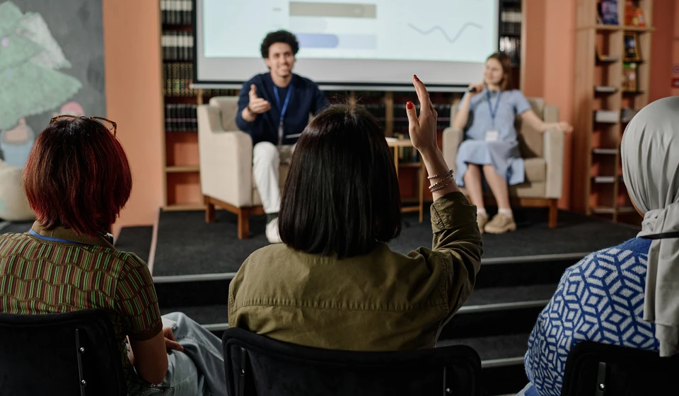 unrecognizable-woman-raising-hand-during-conference